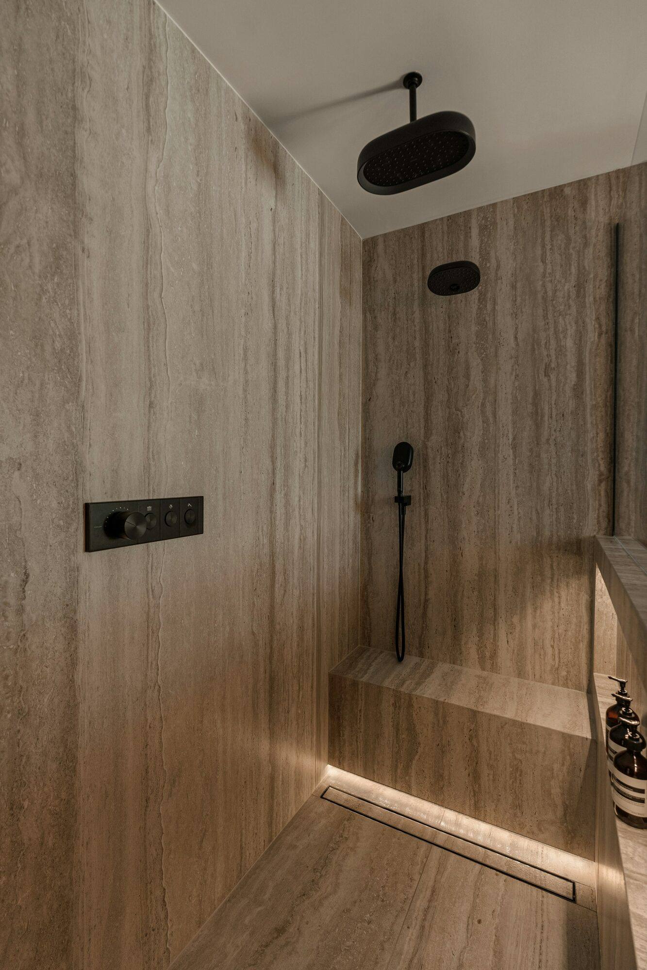 Ducha de obra con banco y revestimiento de piedra
